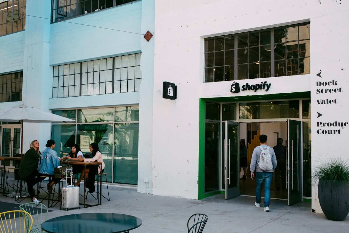 A photo of a white building with the Shopify logo on top of the doorframe