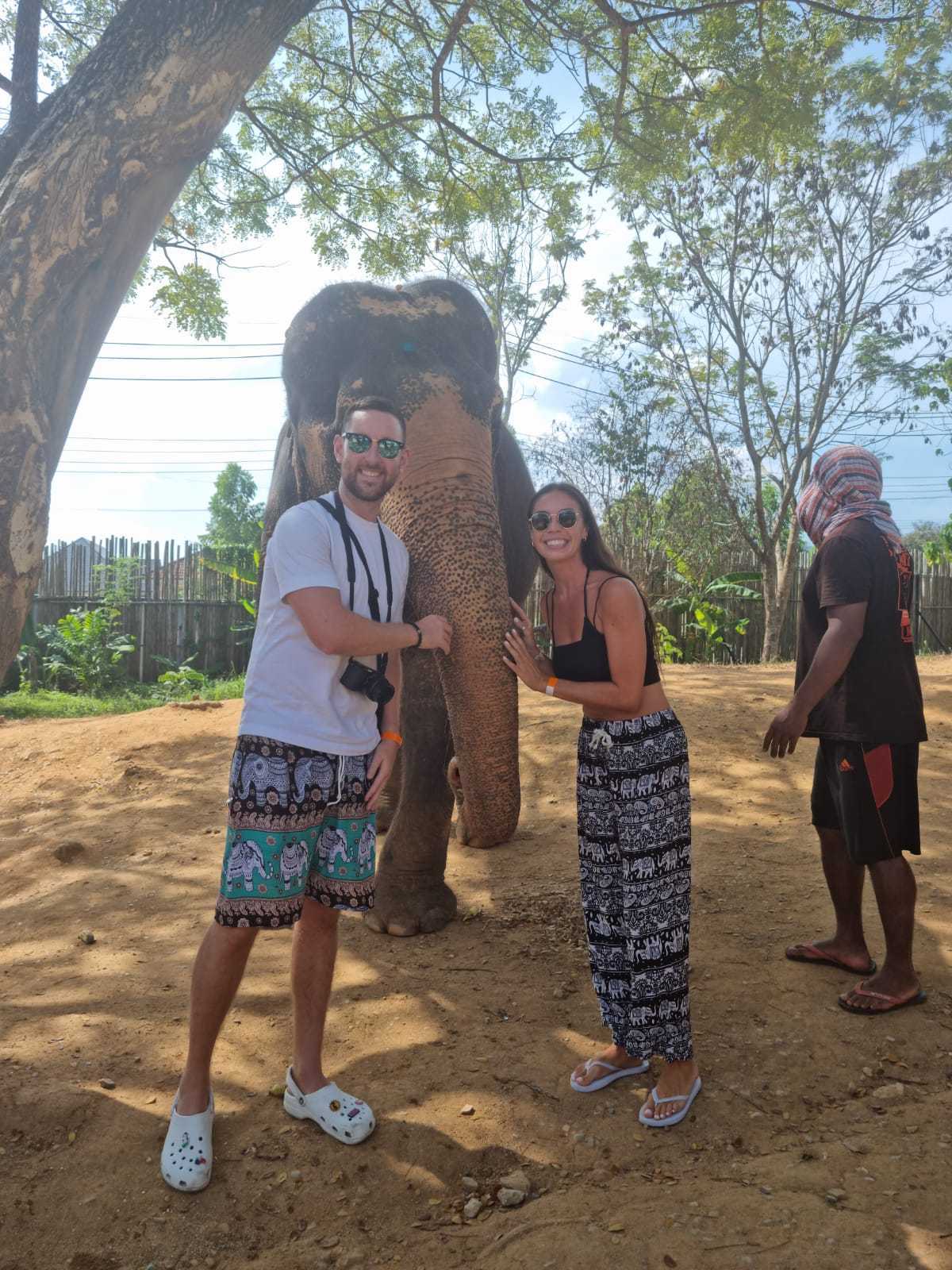 A man and a woman standing in front of an elephant.