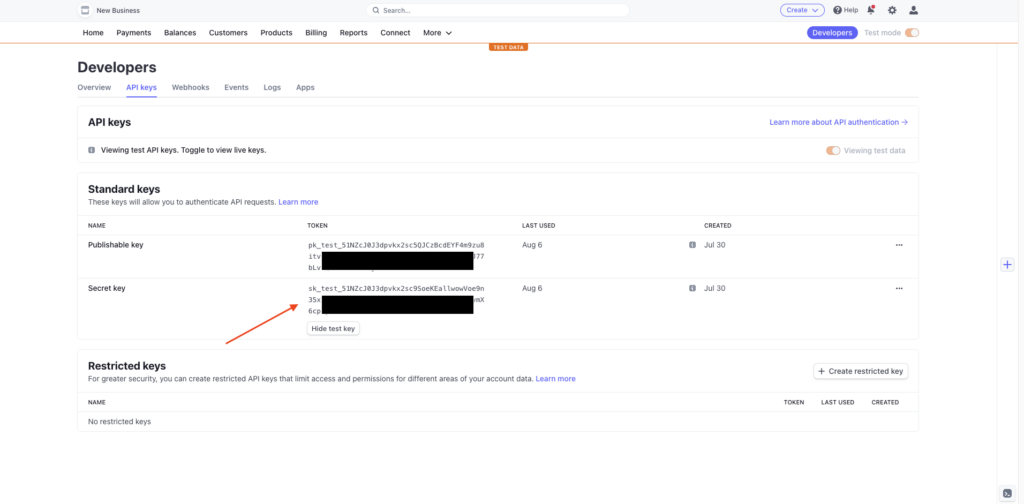  Das Stripe-Dashboard mit einem Pfeil, der anzeigt, wo du nach API-Schlüsseln suchen kannst. Die Schlüssel sind geschwärzt, um sensible Informationen zu verbergen.