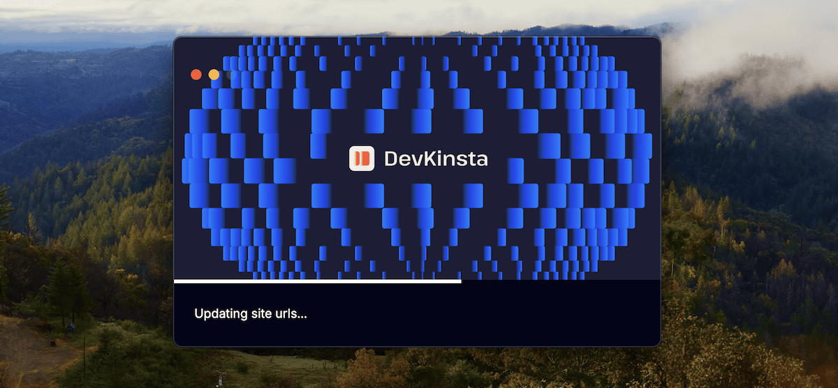 Der Ladebildschirm von DevKinsta. Der Bildschirm zeigt eine dunkle Oberfläche mit dem Namen „DevKinsta“ und einem stilisierten Logo in der Mitte. Das Logo besteht aus einer kantigen, blockigen blauen Form, die aus sich wiederholenden Elementen besteht und dem Buchstaben D ähnelt. Hinter dem Logo befindet sich ein verschwommenes Hintergrundbild eines Waldes mit grünen Bäumen und etwas Nebel. Unter dem Logo steht der Text „Updating site urls...“, was bedeutet, dass die lokale Umgebung gerade konfiguriert wird.